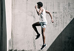 Exercise, fitness and black man jump in city for health, wellness and energy against wall mockup. Sports, training and male athlete jumping, workout or exercising for endurance, practice or strength.