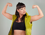 Gen z, woman and flexing arms for empowerment, motivation and against grey studio background. Female, girl and show strength with freedom, winner and style with confidence, strong and trendy fashion