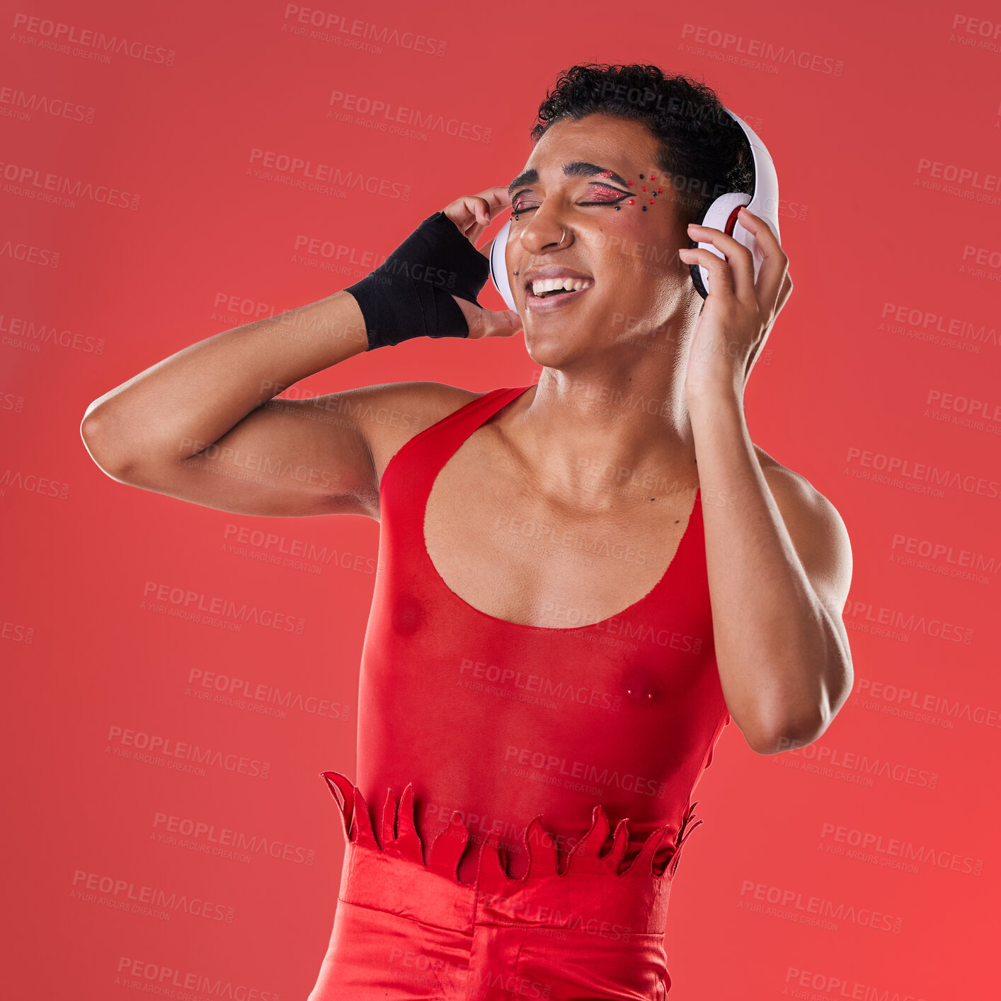 Buy stock photo Dance, music and gay man with headphones isolated on a red background in a studio. Freedom, streaming and dancing lgbt person listening to a podcast, radio and audio on a backdrop for entertainment