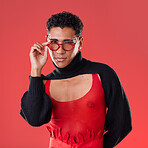 Fashion, portrait and gay man with glasses isolated on a red background in a studio. Lgbt, vision and stylish model person with fashionable eyewear, edgy clothes and funky style on a backdrop