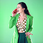 Fashion, phone call and annoyed woman in a studio on a mobile argument, conflict or disagreement. Style, trendy and female model talking on a cellphone with a edgy outfit isolated by green background