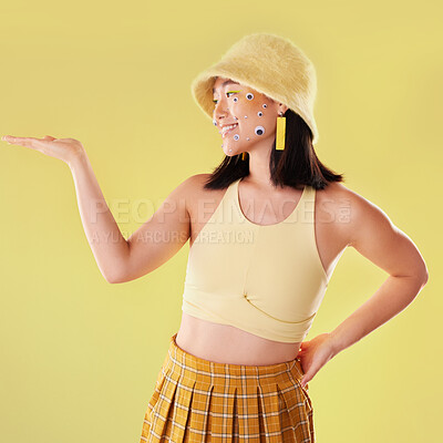 Buy stock photo Fashion, hand and Asian woman with comic eyes isolated on a yellow background in a studio. Happy, funny and stylish girl model with mockup for product placement space, advertising and motivation