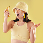 Shock, surprise and woman with a banana in a studio with creative eye stickers on her face. Fruit, fashion and Asian female model with omg, wtf or wow facial expression isolated by yellow background.