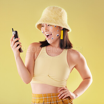 Buy stock photo Asian woman, cellphone and studio for surprise, fashion or eyes sticker art on face with smile for social media. Happy gen z model, 90s aesthetic and phone for communication, chat and app with wow