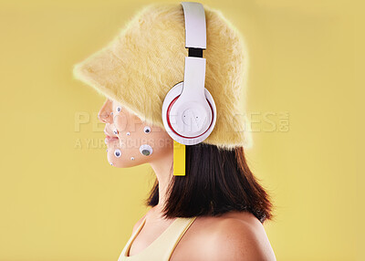Buy stock photo Eye stickers, music headphones and woman in studio isolated on a yellow background mockup. Funny, technology and face profile of female listening, enjoying and streaming radio, podcast and audio.