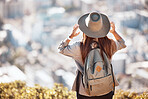 Woman back, mountain and cityscape view for hiking, travel and nature for holiday, summer and wellness goal. Girl, explorer and mountains with city skyline, buildings and looking in morning sunshine