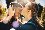 Interracial couple, forehead kiss and smile in nature for love, bonding and embracing relationship. Happy woman kissing man on head smiling for loving care, affection or embrace in a park outdoors