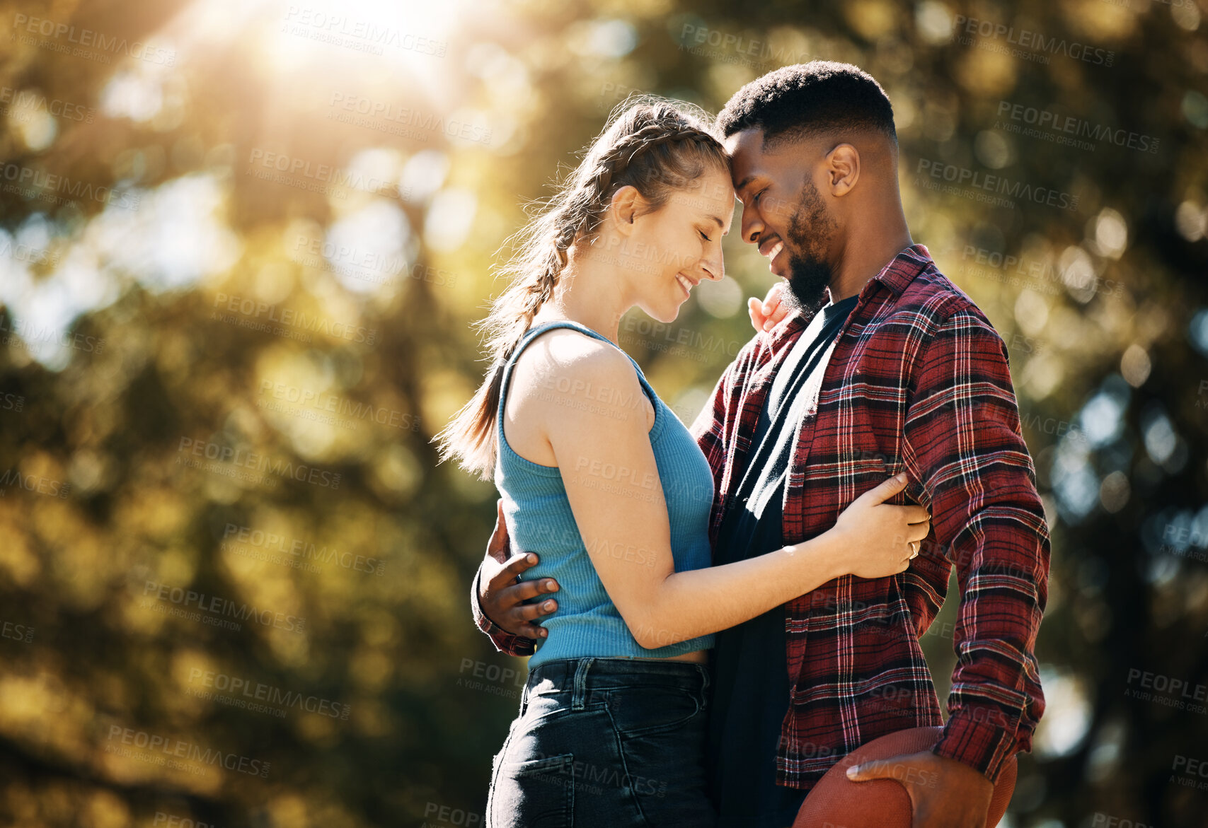 Buy stock photo Interracial couple, outdoor park and love with a hug for commitment, care and nature in summer. Black man and woman together for support, security and date for quality time with trees and lens flare