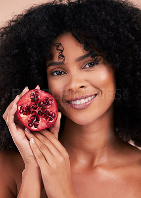 Face, hair care and portrait of black woman with pomegranate in studio  isolated on a brown background. Fruit, skincare and happy female model  holding food for healthy diet, nutrition and vitamin c. |