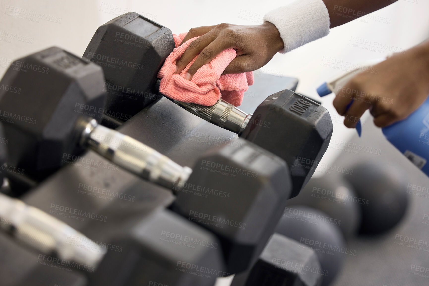 Buy stock photo Dumbbells, cleaner and hands cleaning at a gym with liquid soap in spray bottle with cloth for wellness. Janitor or person wipes dirty bacteria on dusty weights, tools or fitness training equipment 