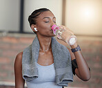 Woman, fitness and drinking water for hydration, workout break or thirsty from intense training at gym. Tired female with bottle or refreshment for thirst, recovery and sweat towel in cardio exercise