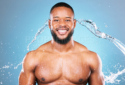 Buy stock photo Muscle, strong and water splash for black man cleaning, hygiene and skincare isolated in studio blue background. Portrait, aqua and model with washing smooth skin with glow smile and happy
