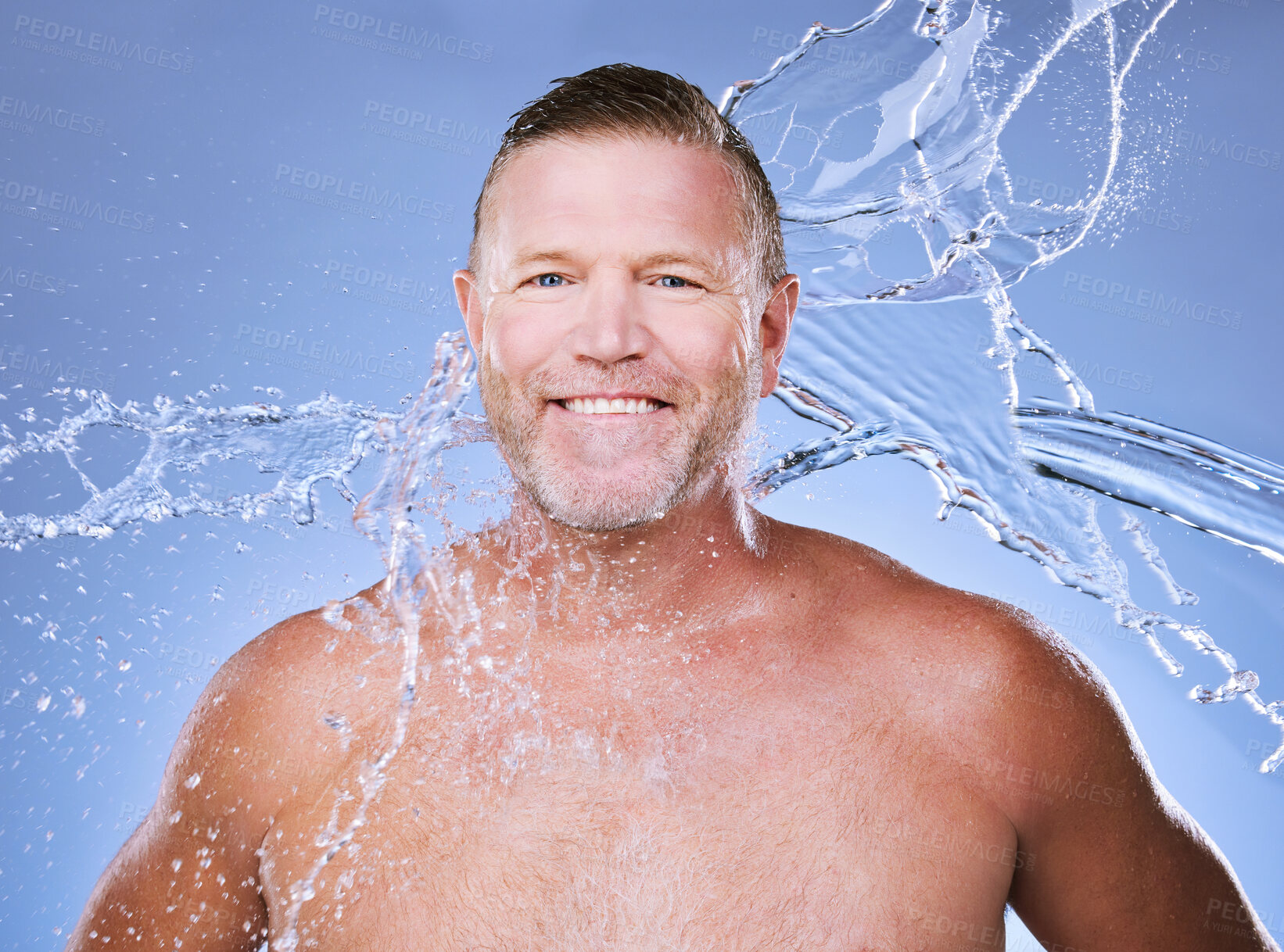 Buy stock photo Portrait, water splash and mature man in studio for cleaning, hygiene and wellness on a blue background. Skincare, face and body care for aging skin of male model in luxury, pamper or beauty routine