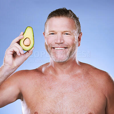 Buy stock photo Beauty, portrait with man and avocado for skincare, eco friendly and vegan cosmetics on blue background. Hygiene, organic product and mature male with smile, detox facial and fruit with face care