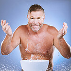 Skincare, water and man washing face in a studio for a beauty, natural and cosmetic routine. Happy, smile and portrait of a senior male model doing a facial cleansing treatment by a purple background