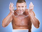 Man cleaning face, portrait and water splash, hygiene and grooming with clean skincare on blue background. Hands washing skin, basin and mature male with cosmetic care, facial and dermatology