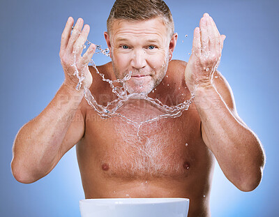 Buy stock photo Man cleaning face, portrait and water splash, hygiene and grooming with clean skincare on blue background. Hands washing skin, basin and mature male with cosmetic care, facial and dermatology