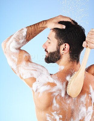 Buy stock photo Shower, cleaning and back of man with water splash, brush and soap for wellness, hygiene and grooming. Skincare, self care and happy male with foam, bath cosmetics and washing body on blue background