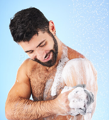 Buy stock photo Body, shower and man with sponge, soap and water splash in studio for wellness, hygiene and grooming. Skincare, cleaning and happy male with foam, bathroom cosmetics and washing on blue background