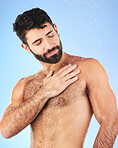 Water drops, shower and man for hygiene self care and cleaning on a blue background in studio. Body of a aesthetic model person for skincare, health and wellness with splash for dermatology cosmetics