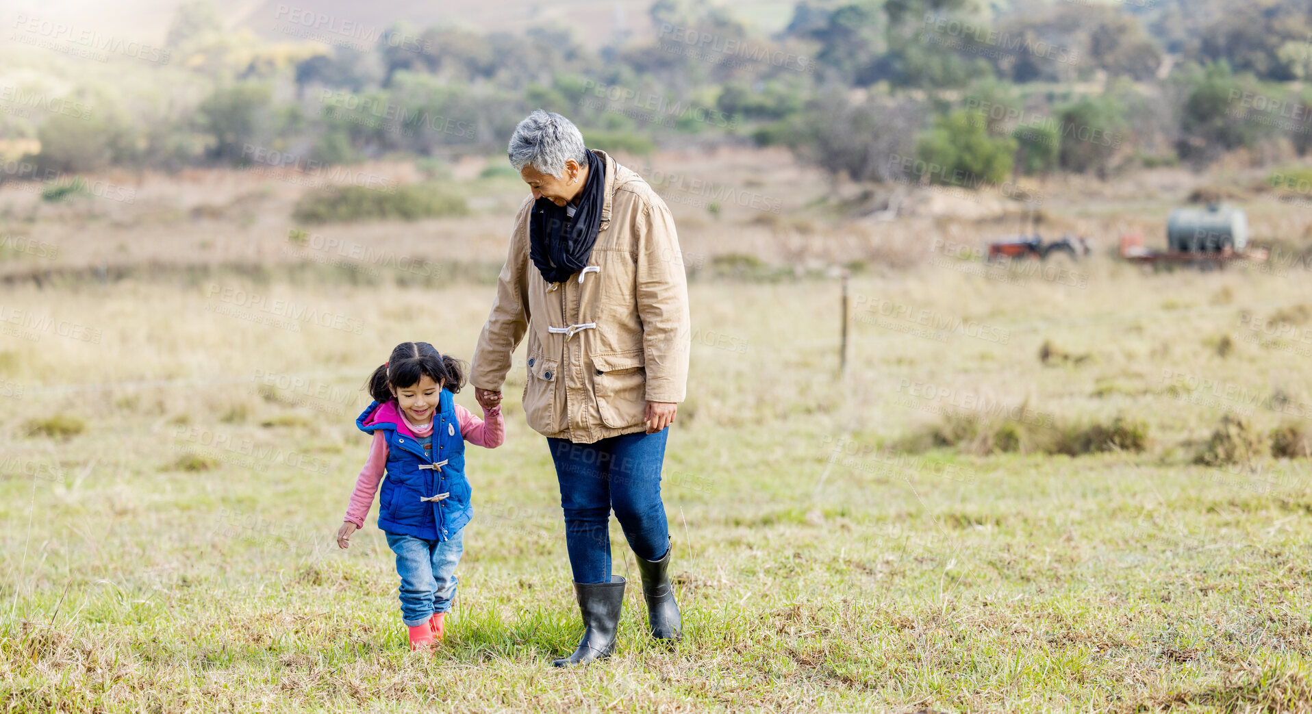 Buy stock photo Grandma, girl and holding hands for walk on grass, family farm and bonding together with love outdoor. Old woman, child and helping hand in countryside, field and happiness in nature with landscape