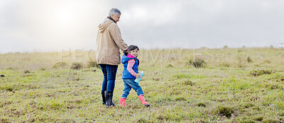 Buy stock photo Grandmother, walking girl and nature park of a kid with senior woman in the countryside. Outdoor field, grass and elderly female with child on a family adventure on vacation with happiness and fun 