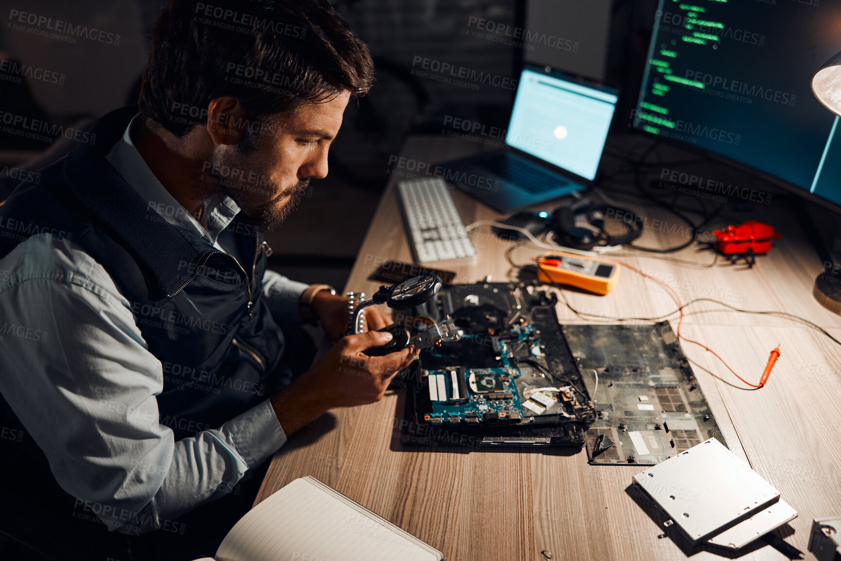 Buy stock photo Night, technician and working on motherboard repair overtime and manufacturing an electronic device in a workshop or shop. Person, man and guy fixing hardware of a computer for technology in a lab