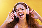 Music, portrait and laughter with a black woman listening to the radio outdoor on a yellow wall background. Headphones, energy and face with an attractive young female streaming audio sound for fun