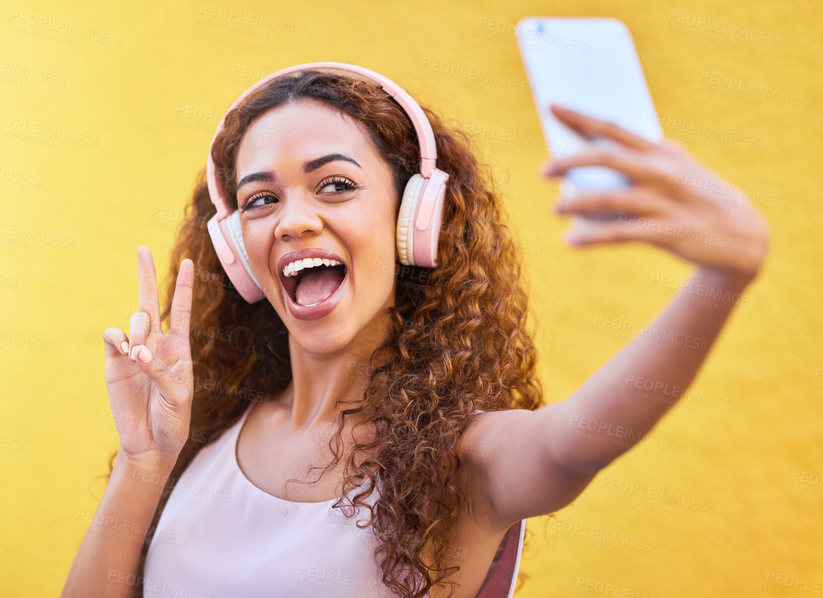 Buy stock photo Black woman, peace selfie and music headphones on yellow wall background for freedom. Happy and excited gen z person outdoor listening to podcast audio with hand sign or emoji for influencer post