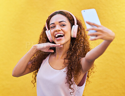 Buy stock photo Music, happy black woman and headphones for selfie on yellow wall background. Face of gen z person with a smile outdoor for listening or streaming motivation audio for influencer post in Colombia