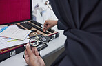 Hands, vision and optometry with an islamic woman at work in eyecare for prescription lenses for sight correction. Doctor, medical or glasses and a muslim female optician working with eyewear