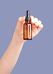 Hands, skincare and serum bottle in studio isolated on a purple background. Product, dermatology and woman or female model with hyaluronic acid, essential oil or cosmetics for aesthetics and beauty.