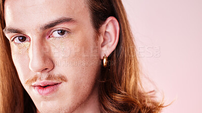 Buy stock photo Face portrait, beauty and man with makeup in studio isolated on a pink background. Gen z, lgbtq and gay, queer or homosexual young male model with gold glitter cosmetics for aesthetics and skincare.