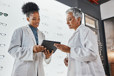 Buy stock photo Tablet, optometrist teamwork and women in shop talking, research or discussing eye test results. Vision, touchscreen technology and senior optician with black woman at glasses store for telehealth.