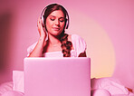 Pink, light and laptop by woman in a bed with music, social media and streaming on wall background. Podcast, website and girl relax in bedroom, happy and enjoying radio, audio or online playlist