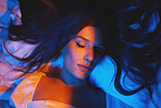 Sleeping, vaporwave lights and woman with eyes closed in bedroom with creative disco lighting. Makeup, beauty and model resting and feeling relax and calm on a bed pillow with cyberpunk aesthetic 