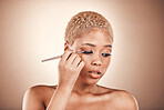 Black woman, beauty and brush for eye makeup on a brown background with cosmetics for face. Aesthetic model person in studio for transformation, self care and facial glow or shine on skin and eyes