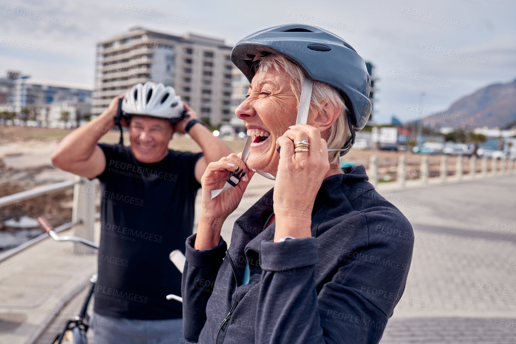 Buy stock photo Helmet, laughter and a senior couple cycling outdoor together for fitness or an active lifestyle. Summer, exercise or humor with a mature man and woman laughing on the promenade during summer