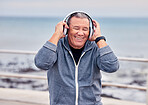 Smile, music and fitness with a senior man outdoor on the promenade for a cardio or endurance workout. Headphones, running and training with a happy mature male outside by the beach for exercise