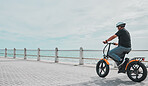 Ebike, mockup and travel with a senior man on the promenade, riding eco friendly transport by the beach. Sustainability, cycling and mock up with a mature male tourist by the seaside for a ride