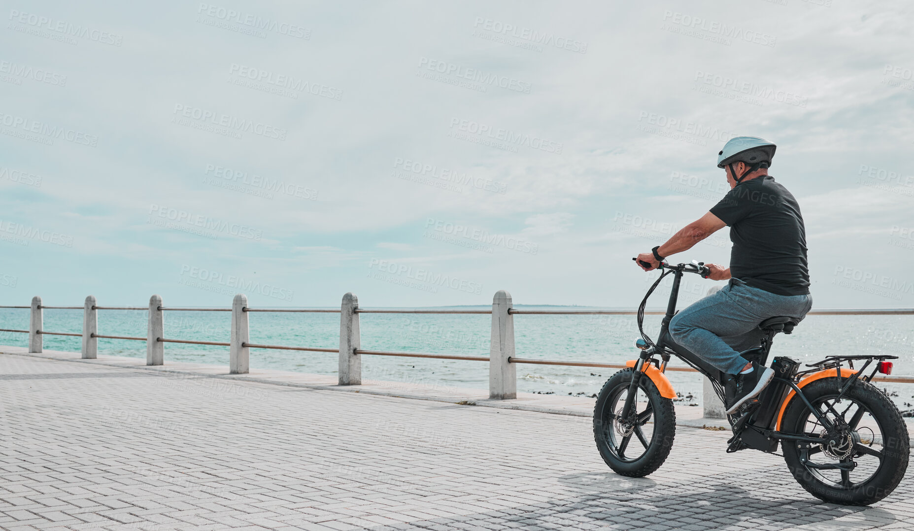 Buy stock photo Ebike, mockup and travel with a senior man on the promenade, riding eco friendly transport by the beach. Sustainability, cycling and mock up with a mature male tourist by the seaside for a ride