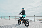 Mature woman, helmet or electrical bike by beach for future fitness, clean energy transport or sustainability travel. Happy person, ebike or electric bicycle with head safety for eco friendly cycling