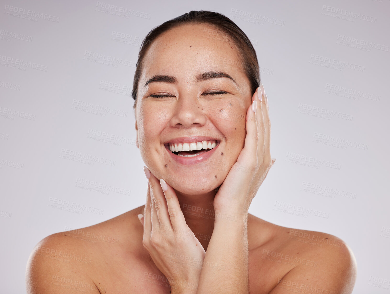 Buy stock photo Skincare, hands on face and woman laughing in studio for cosmetics, dermatology and beauty glow. Happy aesthetic asian model person with makeup, skin mole and facial self care on grey background