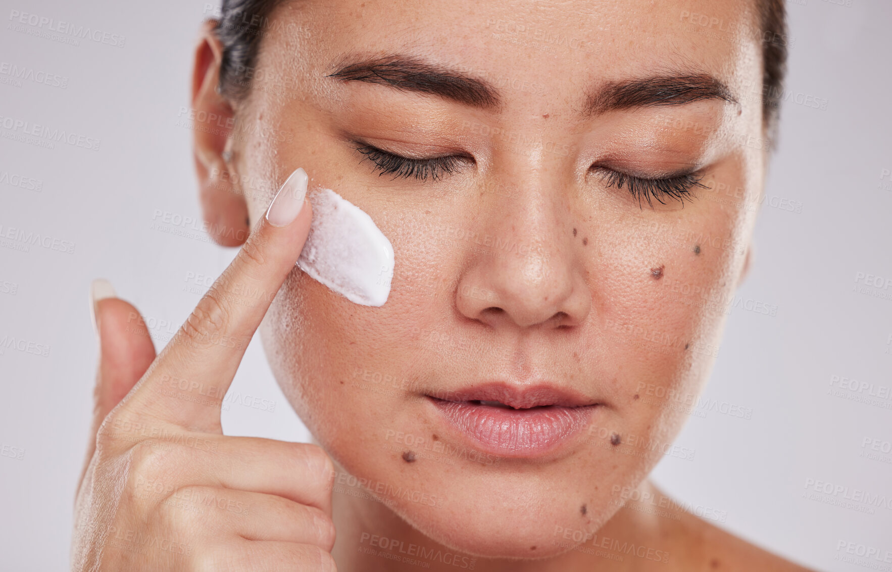 Buy stock photo Skincare, facial and face cream for woman in studio for wellness, grooming and cosmetics on grey background. Sunscreen, model and asian girl relax with luxury beauty, skin and treatment with product