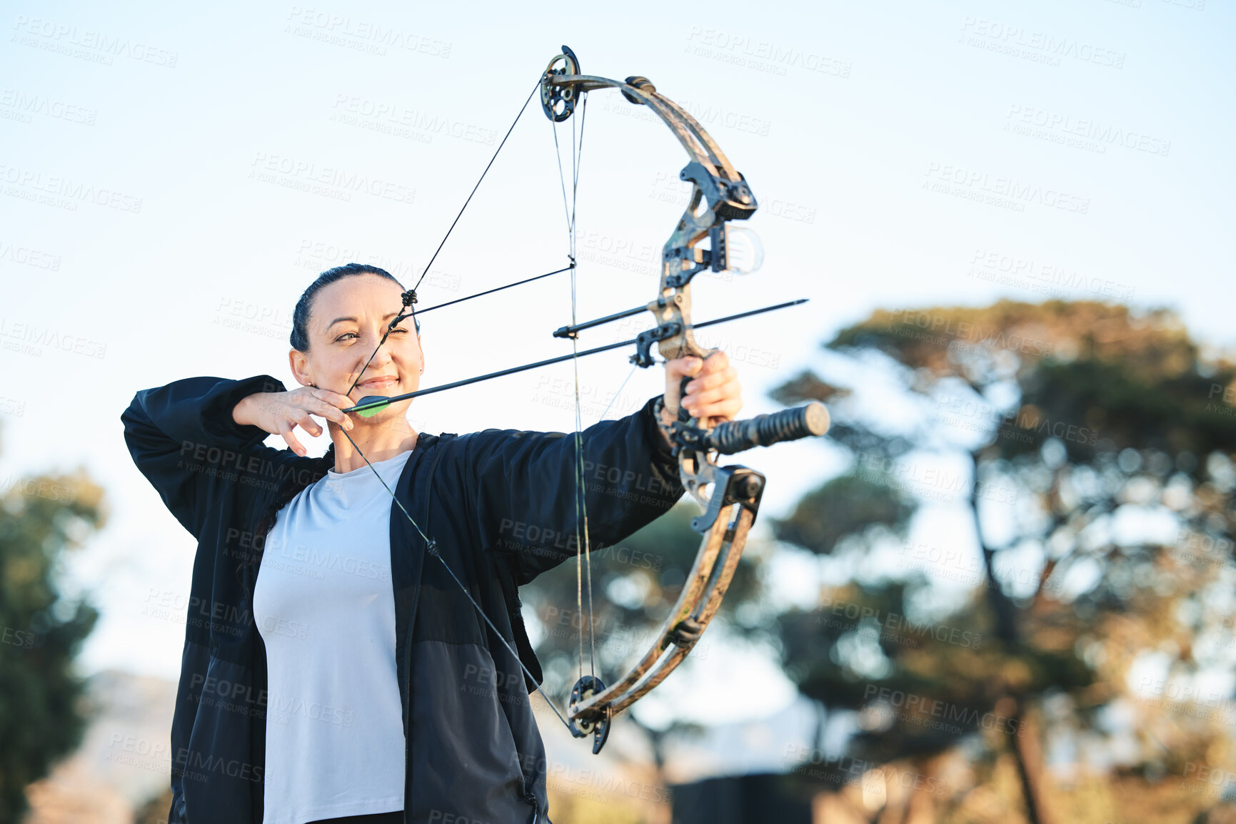 Buy stock photo Happy woman, bow or arrows aim in sports field, shooting range or gaming nature in hunting, hobby or exercise. Archery, person or athlete smile with weapon in target training, competition or practice