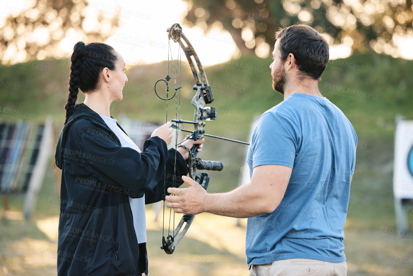 Buy stock photo Target, training and archery woman with an instructor on field for hobby, aim and control. Arrow, practice and archer people together outdoor for hunting, precision and weapon in shooting competition