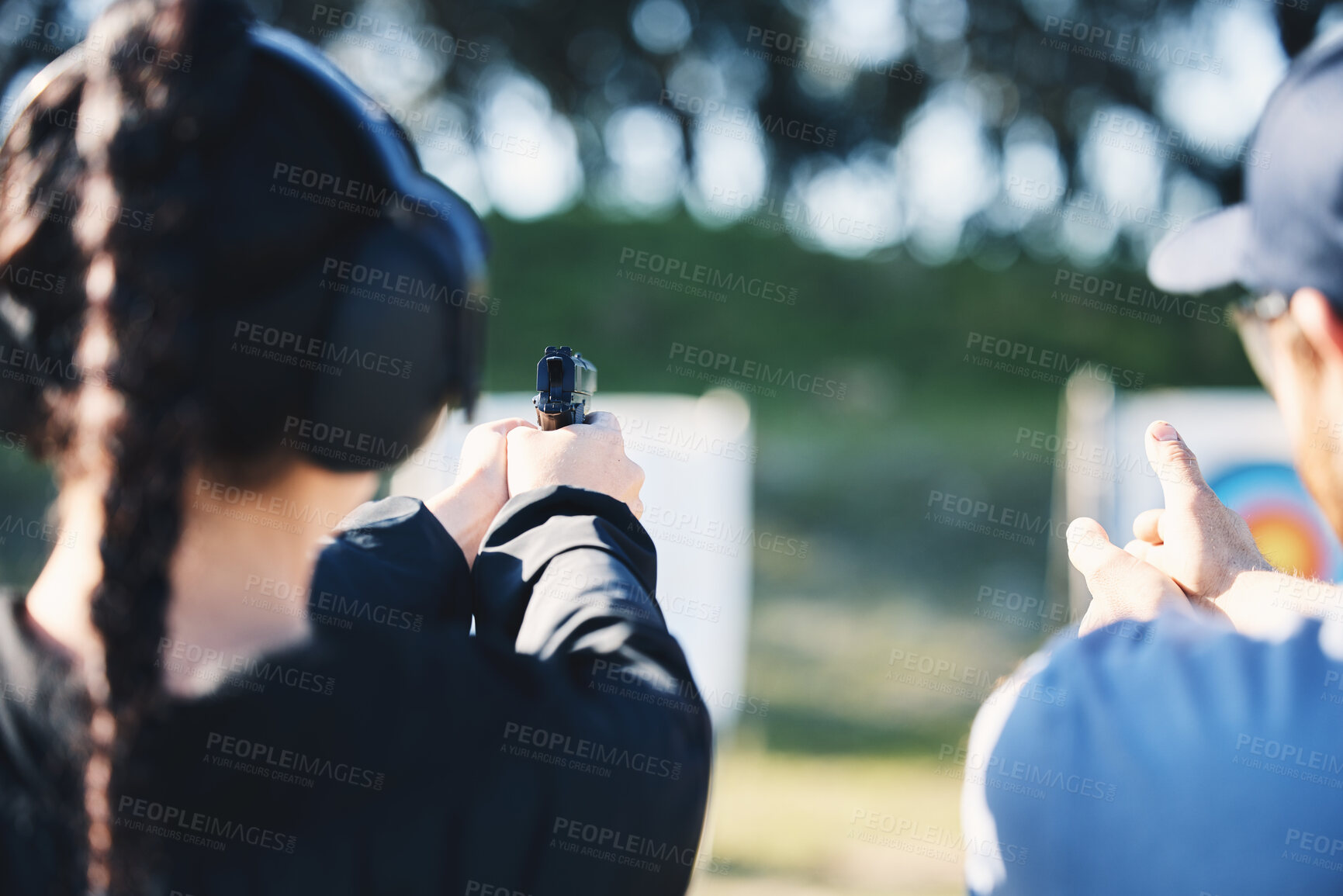 Buy stock photo Woman, gun and learning to shoot outdoor with instructor at shooting range for target training. Safety and security with hand teaching person sport game or aim with gear and firearm for focus