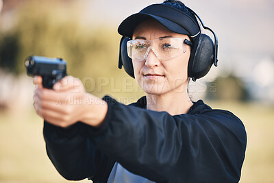 Woman, gun and learning to shoot weapon at shooting range outdoor for security, training and target. Person with safety headphones and glasses for sport, competition or safety with gear in hands