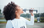 Sports, black woman and drinking water at court during training, workout and sport exercise outdoors. Fitness, thirsty and girl with bottle for wellness, hydration and recovery during practice