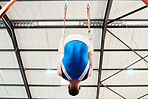 Man, acrobat and gymnastics on rings in fitness for practice, training or workout performance at gym. Professional male gymnast hanging on ring circles for athletics, acrobatics or strength exercise